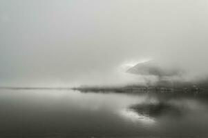 Early foggy  wet morning on the lake between the mountains in Austrian Alps photo