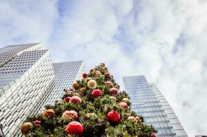 cerca arriba Disparo de un Navidad árbol con moderno edificios en el antecedentes foto