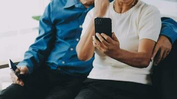 feliz Senior casal usando controlo remoto ao controle para mudança canal. idosos Assistir televisão para entretenimento enquanto homem usando controlo remoto ao controle. esposa e velho homem sentado em sofá dentro vivo quarto com televisão mostrar. video