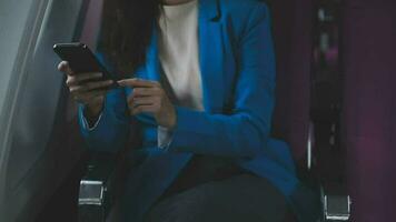 Traveling and technology. Flying at first class. Pretty young businees woman using smartphone while sitting in airplane. video