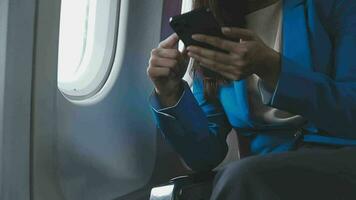 Reisen und Technologie. fliegend beim zuerst Klasse. ziemlich jung Geschäftspartner Frau mit Smartphone während Sitzung im Flugzeug. video
