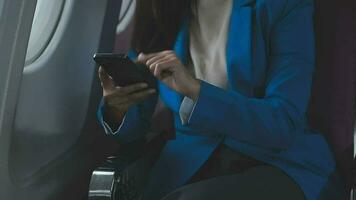 in viaggio e tecnologia. volante a primo classe. bella giovane imprenditori donna utilizzando smartphone mentre seduta nel aereo. video