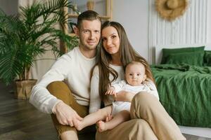 Portrait of Mom, Dad and six-month-old baby son in their arms spending time together in their cozy home photo