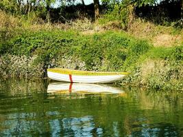 a small boat is sitting on the shore of a river photo