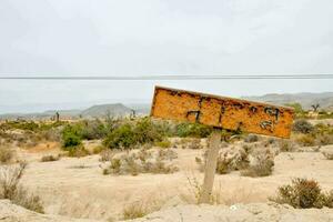 a sign in the desert with a wooden post photo