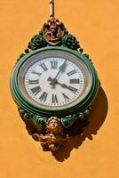 a clock on a yellow wall with green and brown trim photo