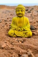 a yellow buddha statue sitting on the ground photo