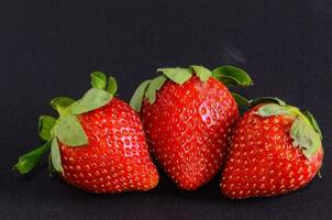 three strawberries on a black background photo