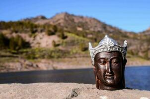 a buddha head on a rock near a lake photo