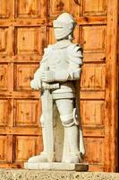 a statue of a knight standing in front of a wooden door photo