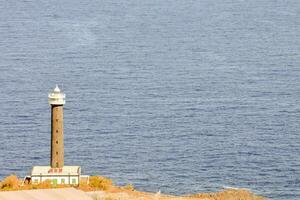 a lighthouse on a cliff overlooking the ocean photo