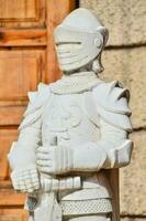 a statue of a knight in armor stands outside photo