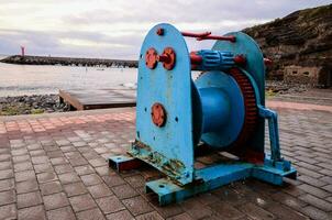 a blue and red machine sitting on the ground near the ocean photo