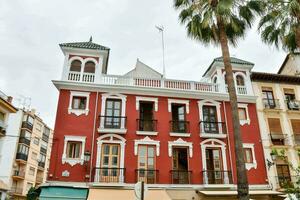 a red building with white trim and palm trees photo