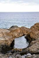 a rock arch over the ocean photo