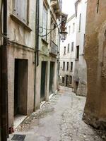 a narrow street with a stone wall and doorways photo