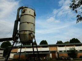an old industrial tank sitting in front of a building photo