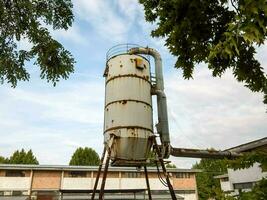 an old industrial water tower in the middle of a field photo