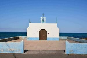 a small chapel on the beach with a cross on top photo