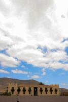 a building under large wite clouds and a blue sky photo