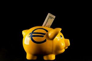 a yellow piggy bank with a euro sign and money sticking out of it photo