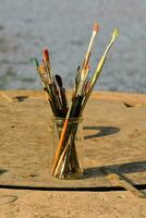 a vase filled with paint brushes sitting on a table photo