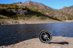 a compass on a rock near a lake photo