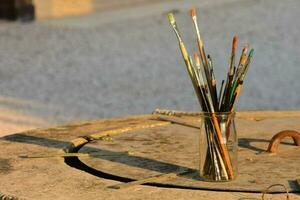 a vase filled with paint brushes on a stone table photo