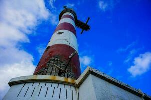 a red and white lighthouse with a blue sky in the background photo