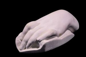 un blanco mano escultura en un negro antecedentes foto