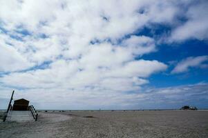 a lifeguard tower on a sandy beach with clouds in the sky photo