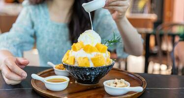 Shaved ice dessert with mango slices. Served with vanilla ice cream and whipped cream. Sweet dessert in Korean style. Local name, Bingsu. photo