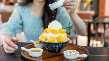 Shaved ice dessert with mango slices. Served with vanilla ice cream and whipped cream. Sweet dessert in Korean style. Local name, Bingsu. photo