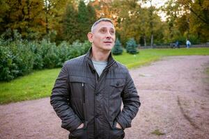 a man in an autumn jacket in the park stands on the path photo