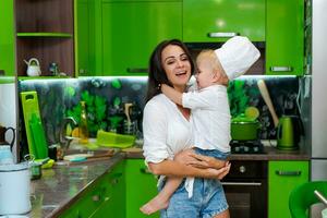 contento familia, madre participación su hijo en su brazos en el cocina foto