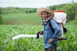 asiático hombre granjero llevar fertilizante rociador máquina en atrás, estar a jardín. concepto, granjero utilizar motor facilitador herramienta en agricultura. fácil y rápido para siembra. foto