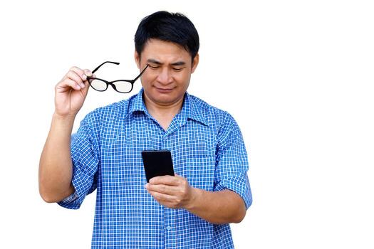 Asian man holds eyeglasses, and looks at smartphone, gentle smile, isolated on white background. Concept, using smartphone with social media in daily life. Eyesight problem for watching on smartphone. photo