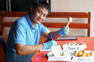 Asian man researcher is doing research and comparing types of  edible wild mushrooms. Concept, study and research about mushrooms which grow in forest in Thailand. photo