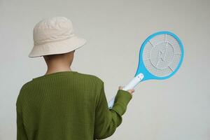 Back view of boy wears hat, holds mosquito electric swatter racket.   Concept, Tecnology electric device to kill mosquitoes, insects, bugs by swatting to flying insects photo