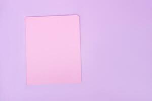 Workplace with photo from above with pink notepad, on isolated purple background, copy space. female business concept