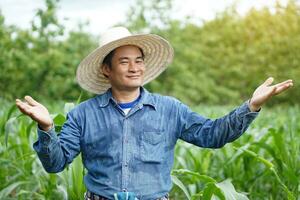 Happy Asian man farmer is at garden, wear hat, blue shirt,  make hands gesture to present product for advertisement at paddy field. Concept , Agriculture occupation. Happy farmer photo