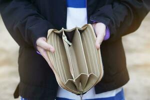 cerca arriba mujer manos sostener vacío bolso con No dinero. concepto, pobre, malo económico crisis. financiero problemas. rompió o Menos dinero a el final de mes. pagar día. foto