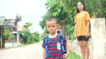 mother sends her son in front of the house to go to school. video