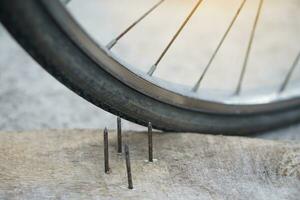 Close up nails on wood board and flat bicycle tire. Concept, unsafe , damage. Be careful and look around during cycling on the floor or risk places. Accident can be happened. photo