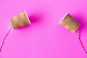 DIY paper cups with string on pink background. Concept, telephone toys which apply with science knowledge about vibration sound through straining strings causing us to hear the sound. photo