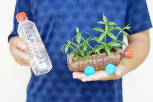 cerca arriba hombre sostiene bricolaje coche cuales crecer plantas, hecho desde el plastico botella y tapas. concepto, jardinería desde reciclar artesanía. reducir, reutilizar y reciclar el plastico basura foto