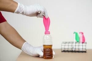 Close up hands doing science experiment with pink balloon, Mix soft drink with baking soda powder  in bottle. Concept, science experiment about reaction of chemical substance. photo