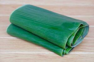 Folded banana leaves for food wrapping on brown wooden background. Concept, package container from nature, safe for wrapping food. Eco friendly and safety for consumers. photo