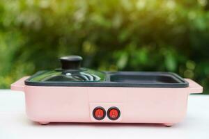 Minimal pink electric pan, placed outdoor. Concept, kitchen utensil. Modern or kitchenware appliances for cooking, can use for grill, boil or fry. Easy to cook. photo