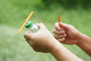 Close up hands hold DIY toy made from plastic bottle, rope and ice cream stick. Concept, Recycle crafts. Toy for kids, Teaching aid, fun activity for active learning. Spin for movement. DIY helicopter photo